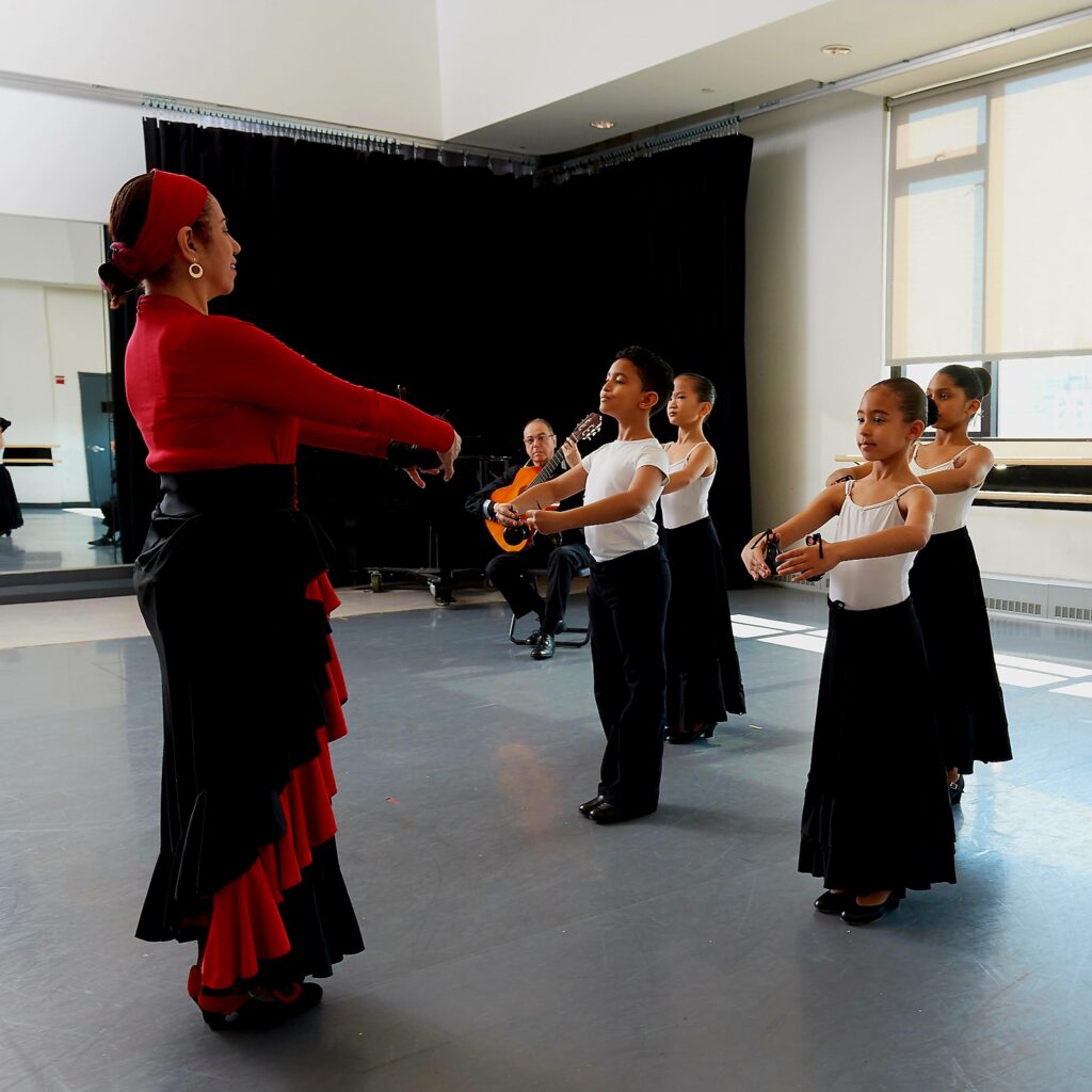 Ballet Hispánico School of Dance photo of teacher teaching child students ballet via Michelle Tabnik PR for use by 360 Magazine